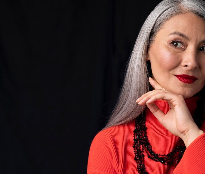 A woman with gray hair styled elegantly, wearing bright red lipstick, exuding confidence and sophistication